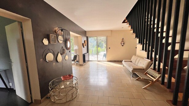 Un vaste espace de vie comprenant un canapé, un fauteuil, une table basse et un escalier doté d’une rampe.