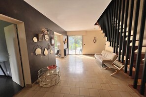 A spacious living area with a sofa, a chair, a coffee table, and a staircase with a railing. - Grand French Family Holiday Home (Saint-Germain sur Bresle)