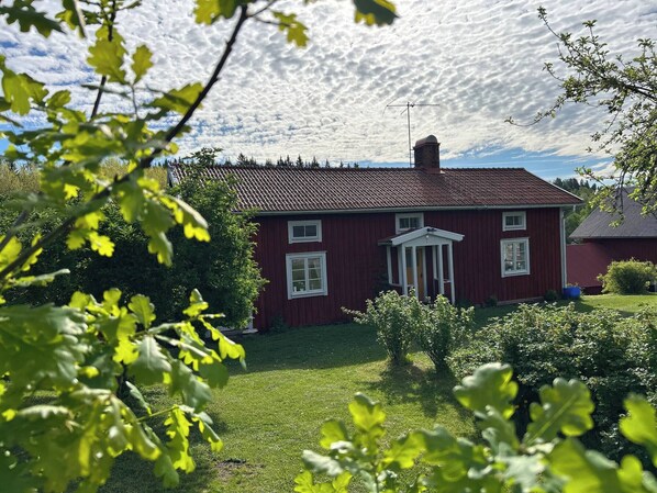 A red house with a white door and windows, surrounded by greenery. - Villa Sakis - Historic Swedish Farm Cottage - Lake & Sauna (Nora)