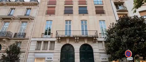A multi-story building with a classic architectural style, featuring a prominent entrance with double doors and a balcony above.