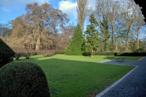 A well-maintained grassy area with a variety of trees and a bench. - Hoefke Voort – Rural farmhouse in Haspengouw, total peace in protected landscape (Tongeren-Borgloon)