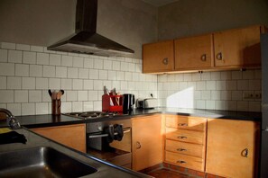 A kitchen with wooden cabinets, a stainless steel sink, a stove, and a toaster. - Hoefke Voort – Rural farmhouse in Haspengouw, total peace in protected landscape (Tongeren-Borgloon)