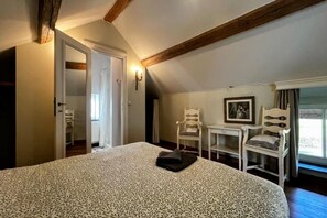 A bedroom with a large bed, a desk, two chairs, and a window. - Hoefke Voort – Rural farmhouse in Haspengouw, total peace in protected landscape (Tongeren-Borgloon)