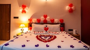 Habitación de hotel con cama, almohadas, una mesita de noche con lámpara y una decoración en la pared.