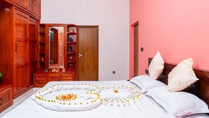 Un dormitorio con cama, armario de madera y pared rosa.