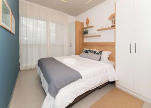 A bedroom with a bed, a window with sheer curtains, a wooden headboard, and a white wardrobe. - Corporate Stays Petra Tower - 34G  (Asunción)