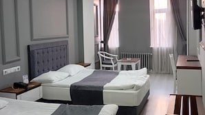 Une chambre d’hôtel avec deux lits, un bureau, une chaise, un radiateur et un téléviseur.