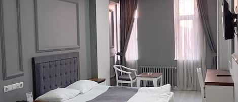 Una habitación de hotel con dos camas, un escritorio, una silla, un radiador y un televisor.