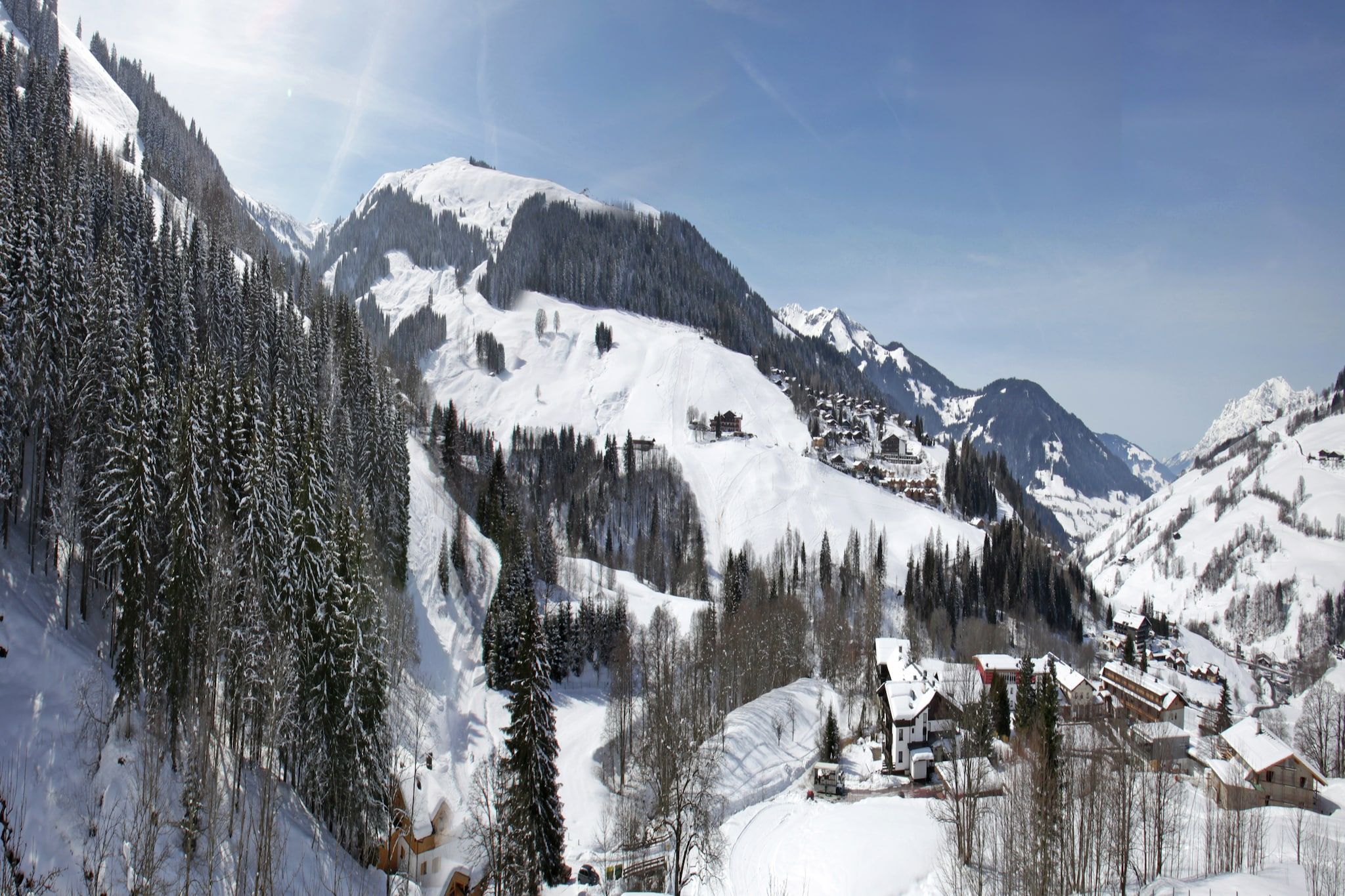 A snow-covered mountain landscape with a village nestled among the trees.