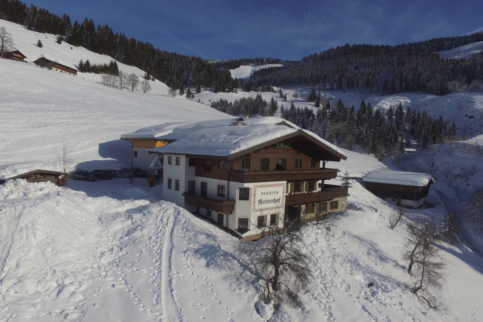 A multi-story building with a snow-covered roof, surrounded by a snowy landscape and trees.
