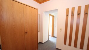 Un corridoio con un'armadio in legno, una porta che dà su un'altra stanza e un parete con listelli di legno verticali.