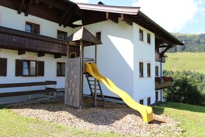 Ein Gebäude mit einem hölzernen Balkon, einer gelben Rutsche und einer Kletterwand.