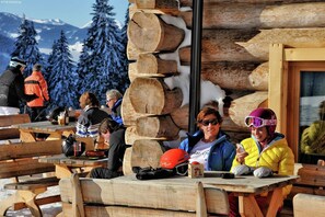 A wooden cabin with a log wall and a table with people sitting at it.