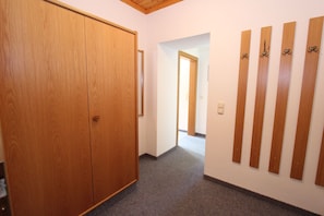 Un couloir avec une armoire en bois, un sol recouvert d’une moquette et un mur orné de lambris verticaux en bois.
