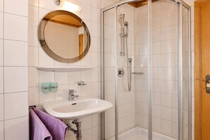 Un baño con ducha, lavabo y espejo.