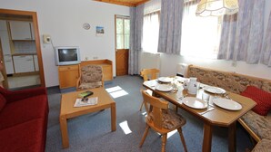 Un accogliente soggiorno con zona pranzo, mobili in legno, televisione e finestra con tende.