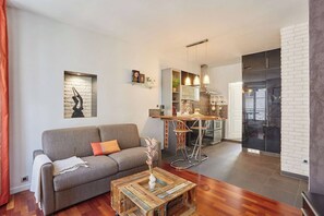 Ein modernes Wohnzimmer mit Sofa, Couchtisch und Küchenbereich mit Barhocker.
