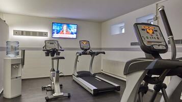 Un gimnasio con cintas de correr, elíptica y dispensador de agua.