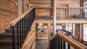 A wooden interior with a staircase, a balcony, and a view of the outside. - Charming Alpine chalet in Weidach (Leutasch)
