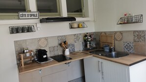 Eine Küche mit Fenster, einer Kaffeemaschine, einem Wasserkocher, einer Spüle und einem Regal mit Küchenutensilien.