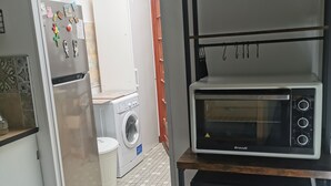 Eine Küche mit Kühlschrank, Waschmaschine und einer Brandt-Mikrowelle.