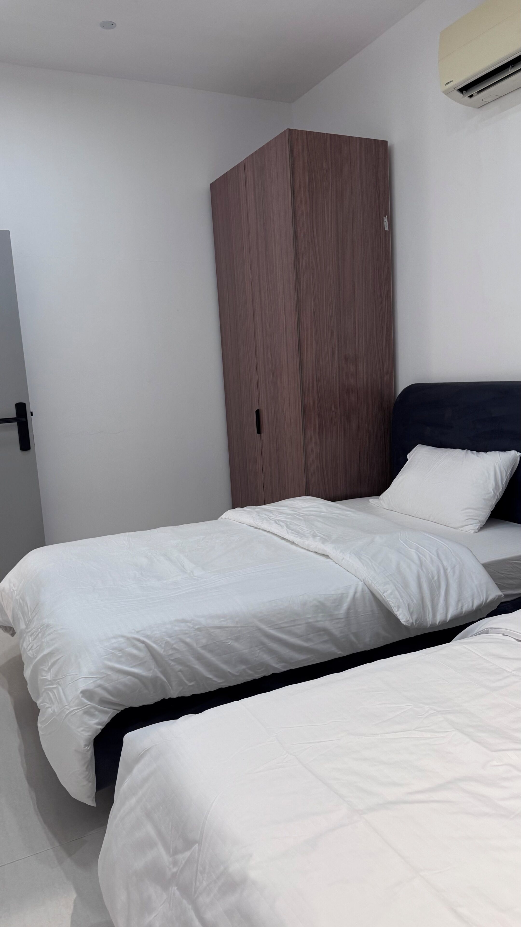 Ein Schlafzimmer mit zwei Betten, einem Kleiderschrank und einer Klimaanlage.