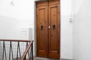 A wooden double door with metal handles, a white wall, and a metal railing. - San Lorenzo Living Apt (Florence)