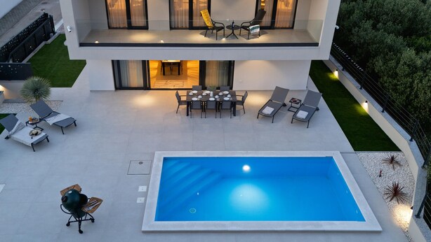 Una casa moderna a due piani con piscina, area salotto esterna e zona pranzo.