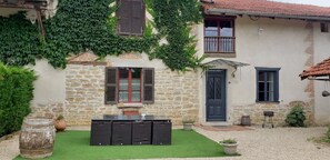 A stone building with ivy, a door, and a window with shutters. - Gîte de la ferme du Tilleul – sleeps 9 guests (Foissiat)