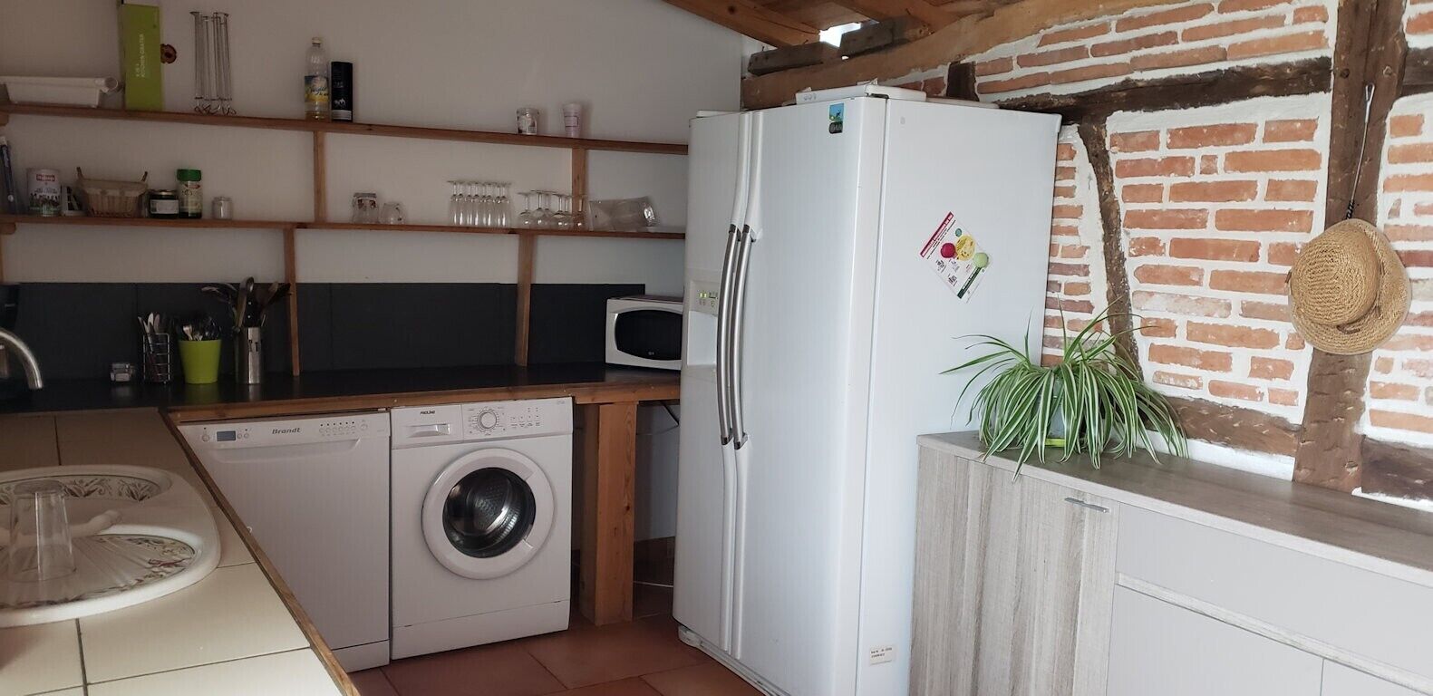 A compact kitchen with a washing machine, a refrigerator, and a microwave.
