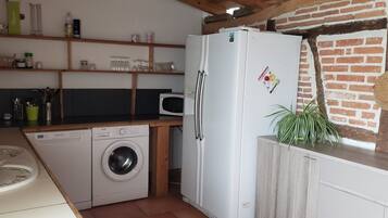 A compact kitchen with a washing machine, a refrigerator, and a microwave.