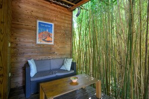 Eine Holzwand mit einem Poster, ein graues Sofa mit gemusterten Kissen und ein Holztisch mit einer Schüssel.