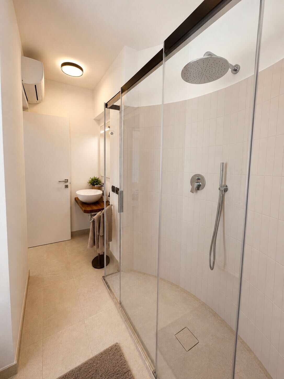 A modern bathroom with a glass-enclosed shower, a sink with a bowl, and a towel rack.