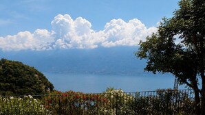 Una terrazza con mobili in vimini, un tavolo rotondo con cose per la colazione e vista sul mare e sulle montagne.
