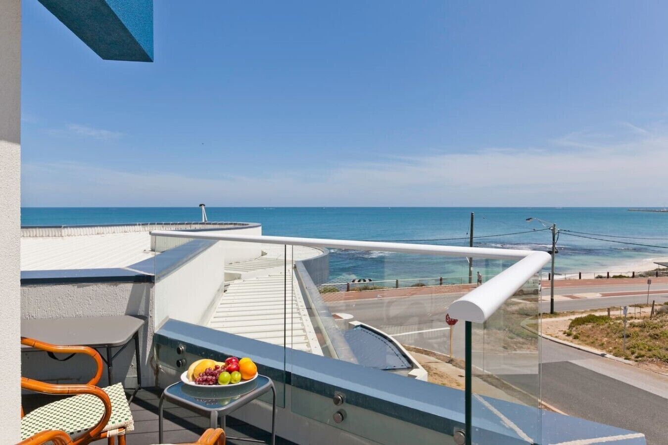 A balcony with a table, chairs, and a view of the ocean.
