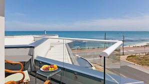 Ein Balkon mit Tisch, Stühlen und Blick aufs Meer.
