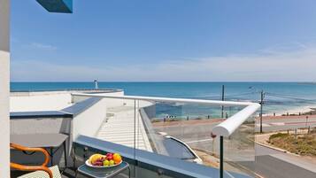 A balcony with a table, chairs, and a view of the ocean.
