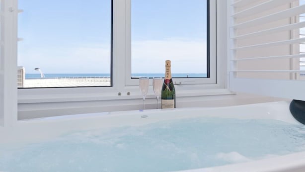 Ein Zimmer mit großem Fenster, Whirlpool und einer Champagnerflasche.