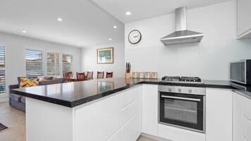 A modern kitchen with a central island, built-in oven, stainless steel range hood, and a microwave.