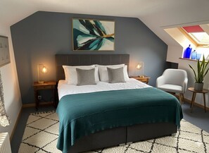 A bedroom with a bed, two bedside tables, a chair, a potted plant, and a skylight. - Les Vieux Toits (Laténa)