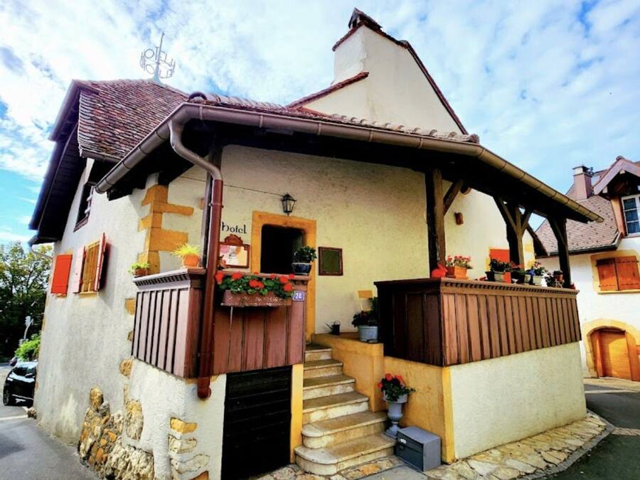 A traditional building with a stone facade, a wooden staircase, and a small porch area with potted plants.