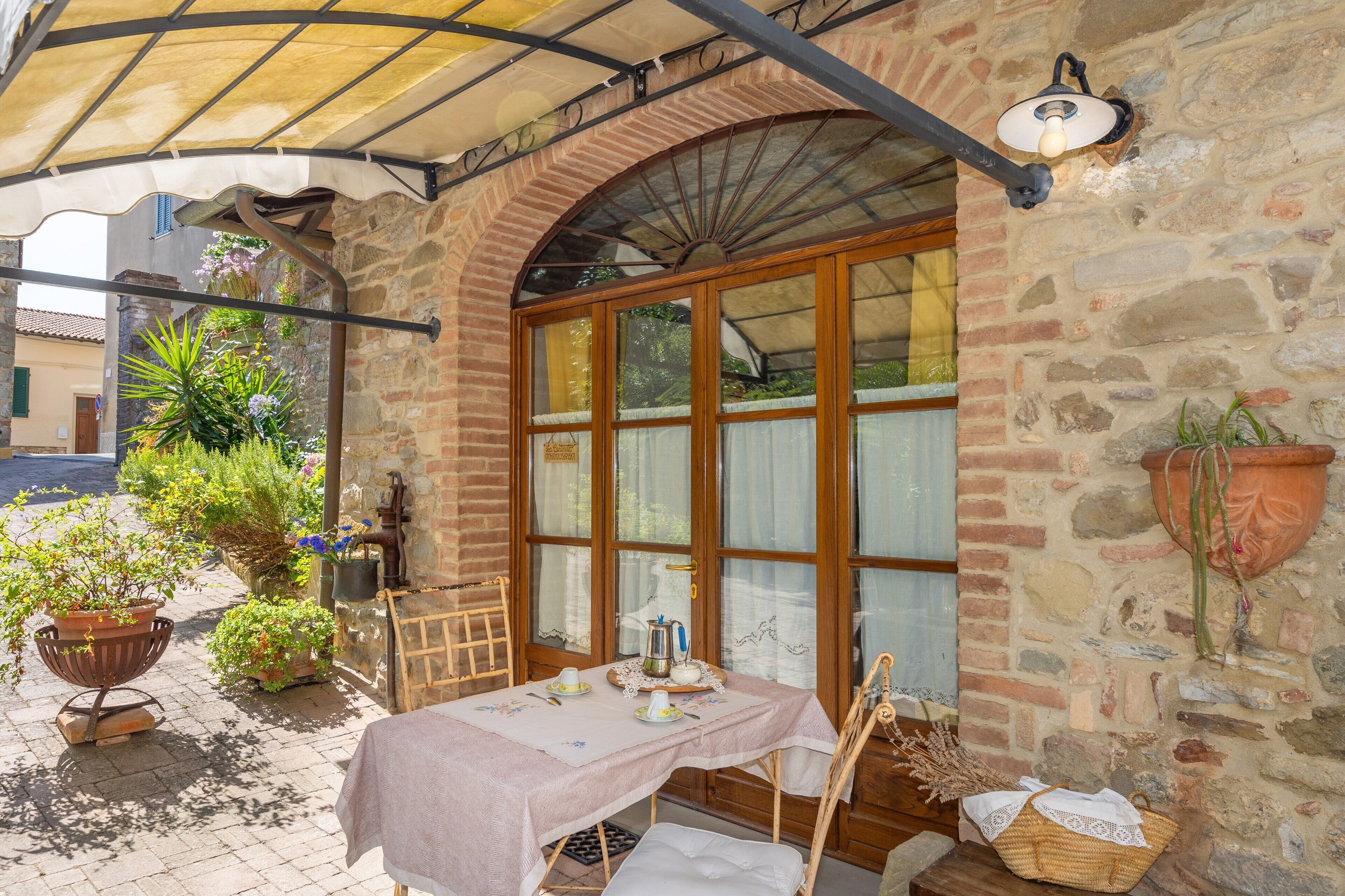 A stone building with a wooden door, a table with a tablecloth, and potted plants.