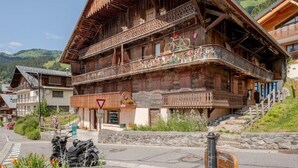 Un tipico chalet in legno con balconi, una insegna ben visibile e montagne sullo sfondo.