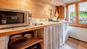 Una cucina con pareti in legno, un forno a microonde, un lavandino e una finestra con vista sul verde.