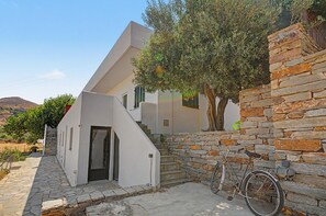 A modern building with a stone wall and a bicycle parked against it. - Holiday Home 'The By The Sea' with Shared Garden, Balcony and Wi-Fi (Otzias)