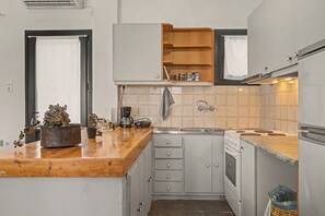 Une cuisine compacte dotée d’un plan de travail en bois, d’un four encastré et d’un évier.