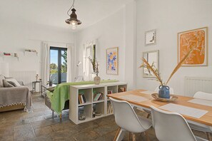 Une pièce bien éclairée, avec une table à manger, des chaises, une bibliothèque et une fenêtre avec des rideaux.
