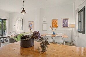 Een eethoek met een houten tafel, stoelen en een vaas gedroogde bloemen.