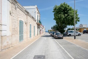 A street with parked cars, a building with stone walls and shutters, and a tree. - A modern and bright 83-square-meter apartment, perfect for five people, located on the first floor of a recently built building with an elevator (NOT accessible to people with disabilities).The property is situated in a quiet area, ideal for those wishin (Bari)
