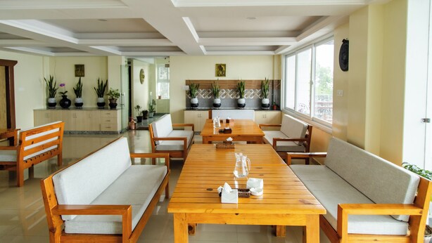 Un comedor con mesa de madera, bancos acolchados y plantas en macetas.